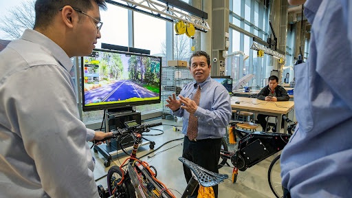 Professor of Electrical and Computer Engineering Romel Gomez works with students for the E–Bike MPact Challenge in the A. James Clark Building’s Leidos Hall. Photo by John T. Consoli
